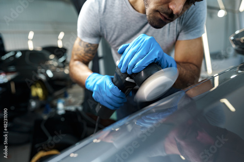 Car detailing. Male hands with orbital polisher in auto repair shop