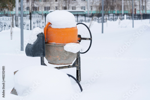 Electric concrete mixer under the snow yf abandoned construction site in Russia.