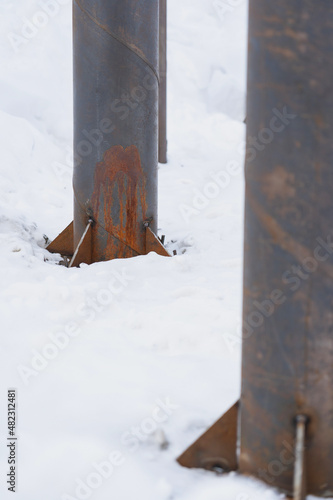 round metal column support on the construction site in winter, selective focus © Larisa
