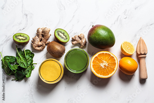 Yellow mango smoothie and green spinach smoothie with ingredients on white background. Detox drinks concept.