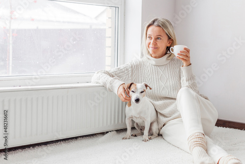 Relaxed, serene adult woman drinking cup of coffee on the sofa in the living room