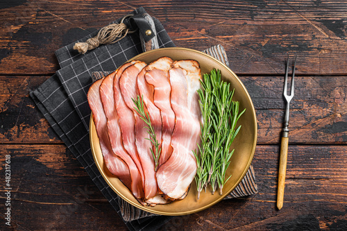 Dry cured pork Black Forest Ham bacon with rosemary. Wooden background. Top view photo