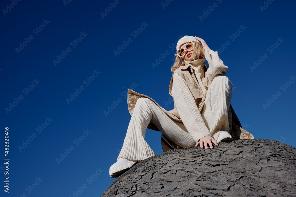 Fototapeta premium young woman sitting on a stone nature blue sky in a hat lifestyle