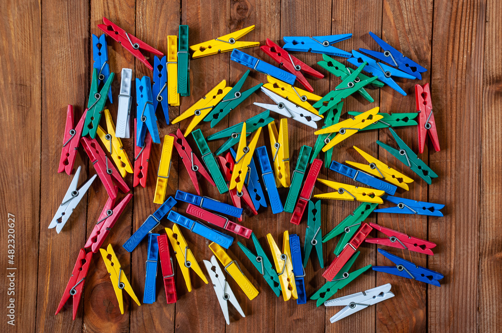 Multi-colored plastic clothespins on a wooden table. View from above.