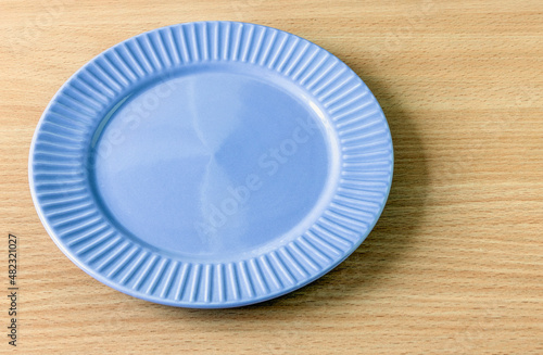 An empty blue plate on a table surface