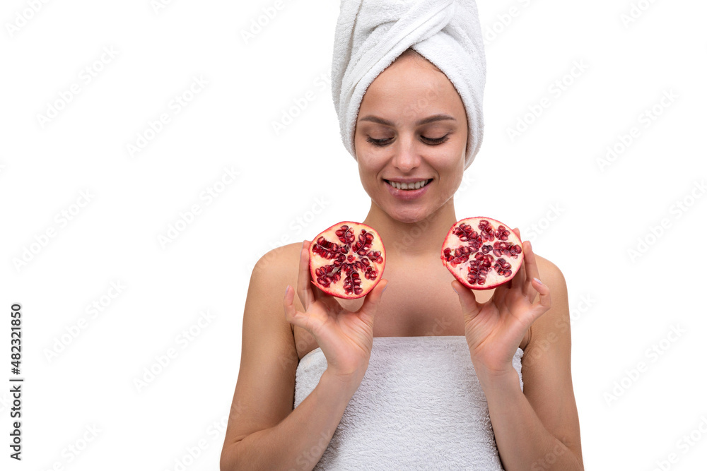 young woman after spa treatments holding a cut pomegranate in her hands on a white background young woman after spa treatments holding a cut pomegranate in her hands on a white background