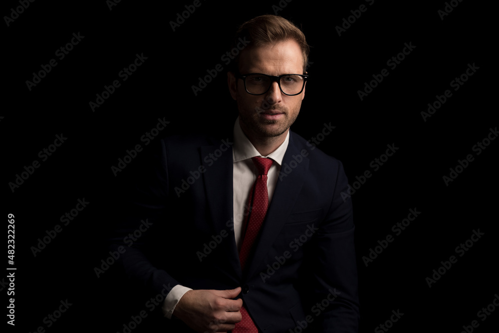 businessman adjusting his suit, wearing eyeglasses and posing