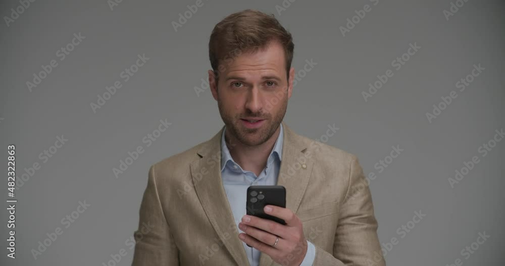 handsome businessman writing on his phone then pointing at the camera handsome businessman writing on his phone then pointing at the camera