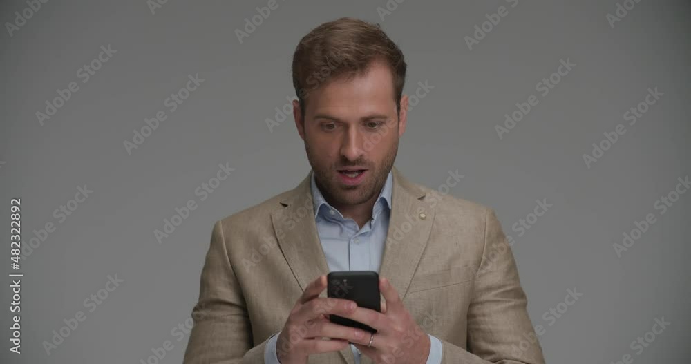 attractive businessman feeling shocked of the news he received from his phone attractive businessman feeling shocked of the news he received from his phone