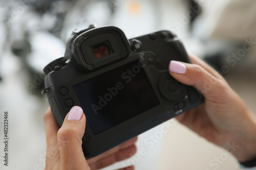 Female hands are holding a black modern camera © H_Ko