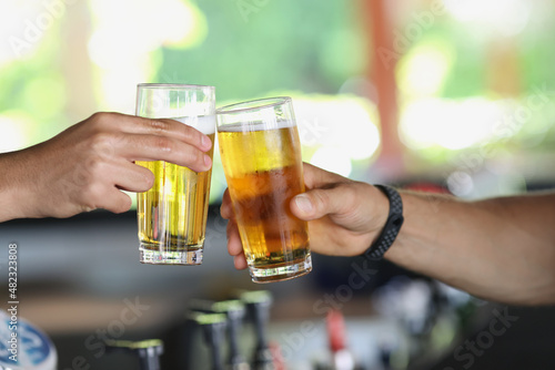 Male hands with glasses of beer clink glasses