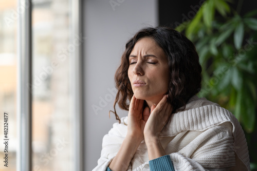 Frustrated woman touch neck check glands during cold, fever and seasonal influenza. Girl suffer from painful throat, ache, swallowing difficulties and loss of voice from angina or coronavirus illness