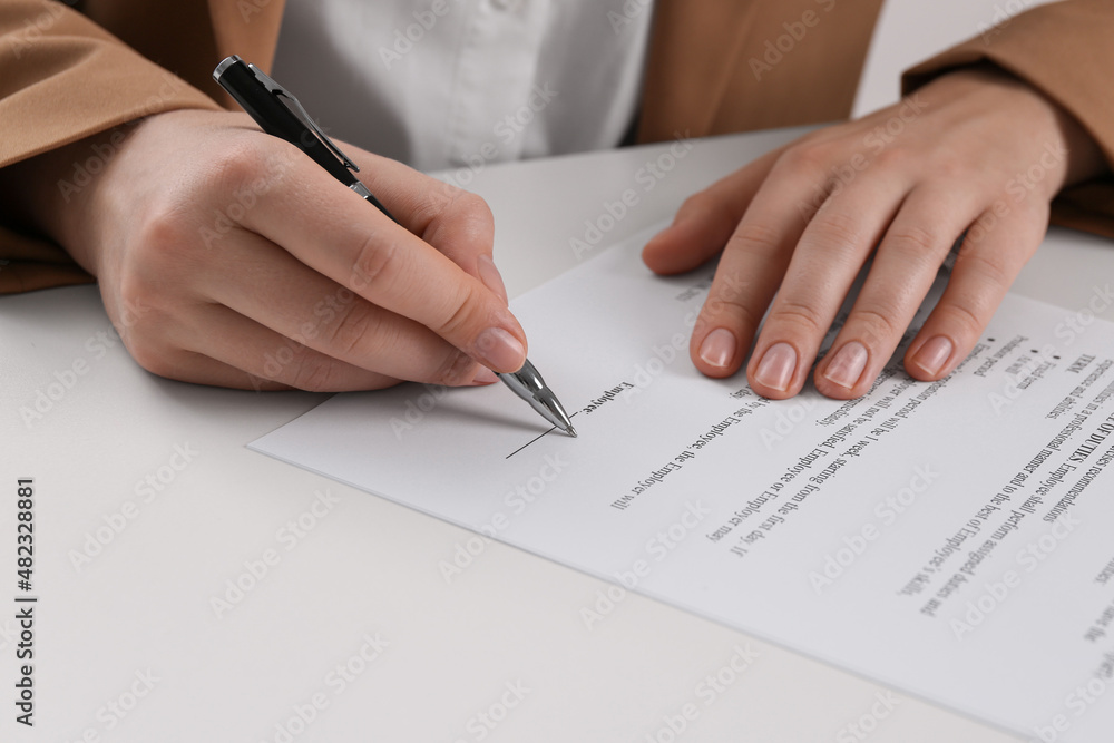 Businesswoman signing contract at white table, closeup of hands Businesswoman signing contract at white table, closeup of hands