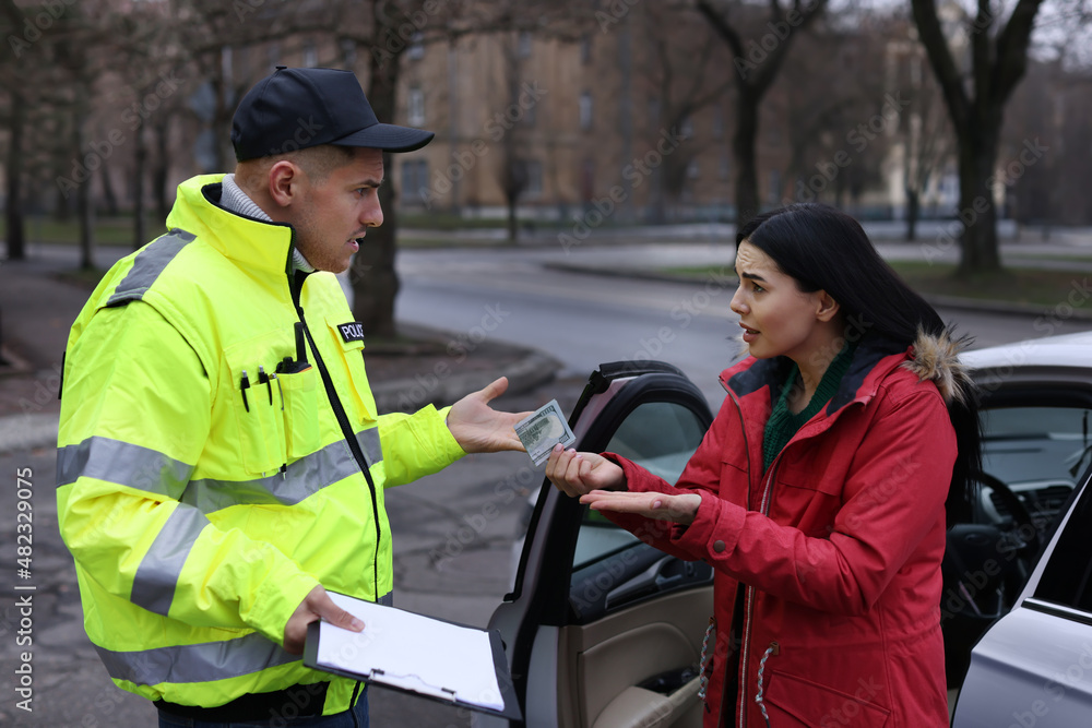 Woman giving bribe to police officer near car outdoors Woman giving bribe to police officer near car outdoors