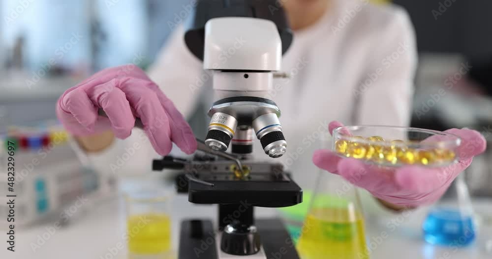Scientist chemist examining medical capsules of omega3 amino acids under microscope 4k movie