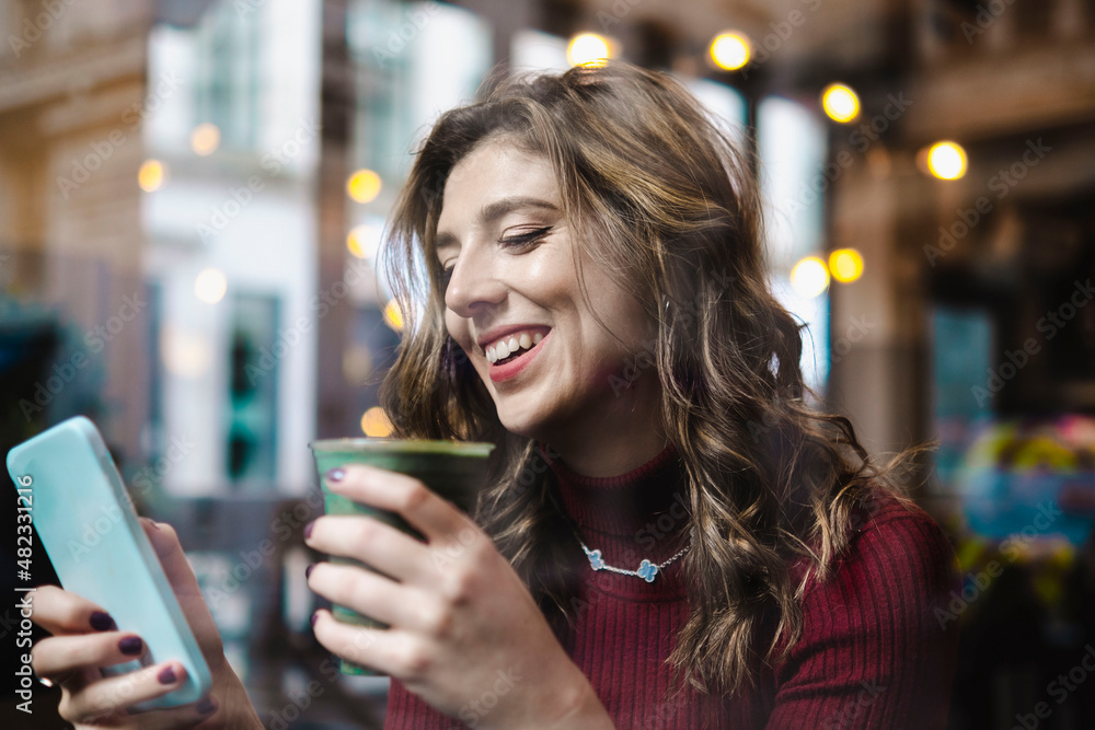 Smiling woman with disposable coffee cup using smart phone in cafe Smiling woman with disposable coffee cup using smart phone in cafe