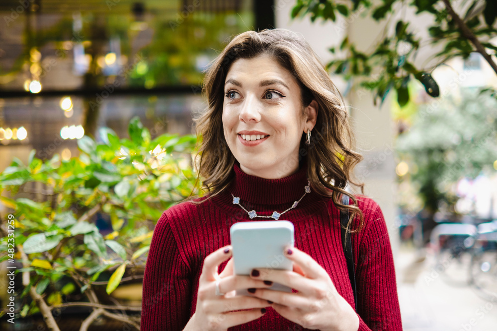 Smiling woman day dreaming with mobile phone Smiling woman day dreaming with mobile phone