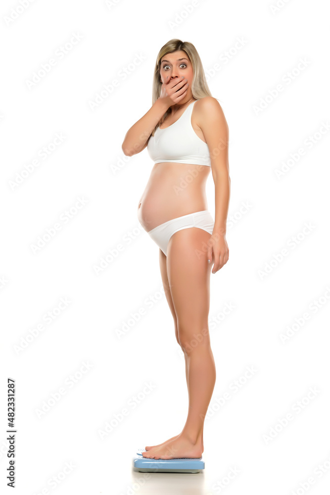 Obraz premium Young shocked pregnant woman standing on a scale