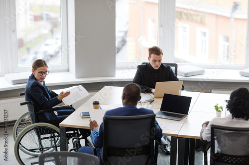 Portrait of successful businesswoman using wheelchair while leading board meeting in office, copy space
