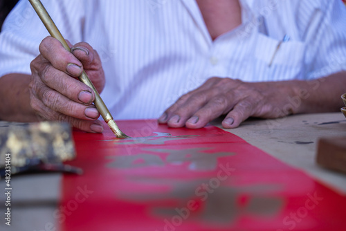 People write Spring Festival couplets with brushes to celebrate Chinese New Year. Chinese New Year scroll with gold ingot and paintbrush. Chinese text translation: Happiness, lucky and wealth.