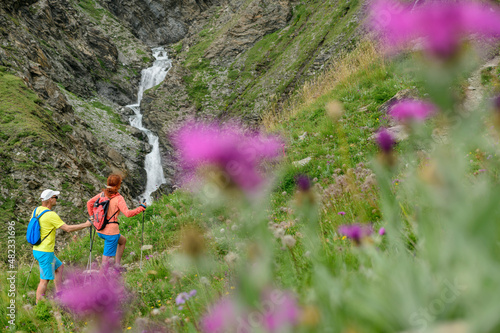 Hiker friends looking at waterfall on mountain Col de l'Iseran, Vanoise National Park, France photo