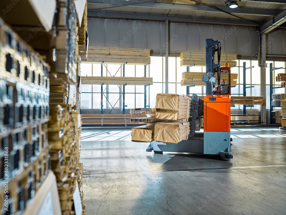 Warehouse worker operating forklift in industrial building Warehouse worker operating forklift in industrial building