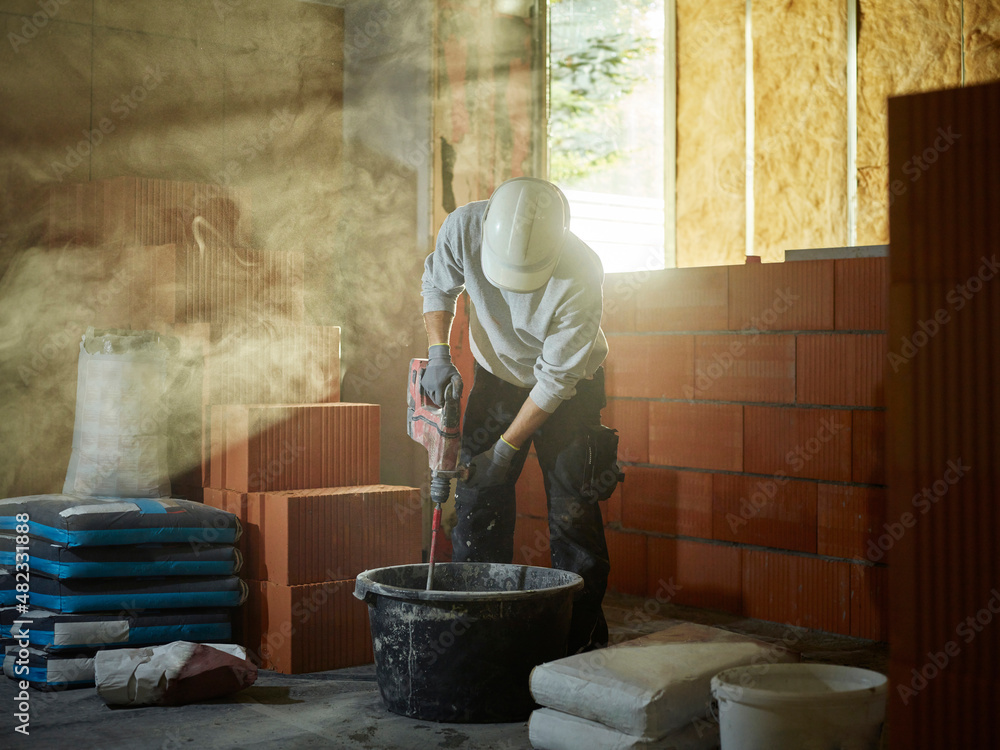 Bricklayer mixing cement in tub at construction site Bricklayer mixing cement in tub at construction site