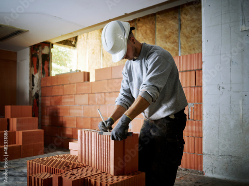 Bricklayer marking on bricks working at construction site photo