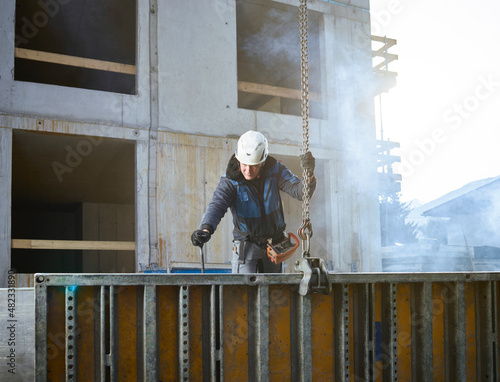 Worker holding chain attached with construction material at site