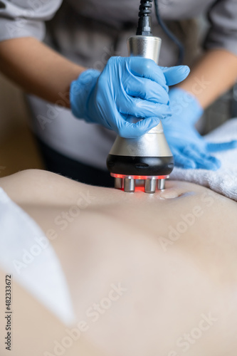 Cosmetology. A woman in a spa clinic receives an RF lifting procedure on a preparation for the abdomen and hips