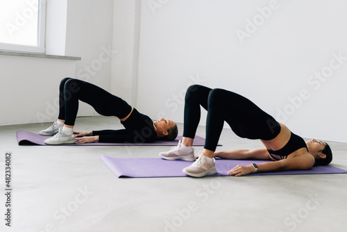 Young fit two women at the gym doing abs workout on a mat, healthy lifestyle and fitness concept
