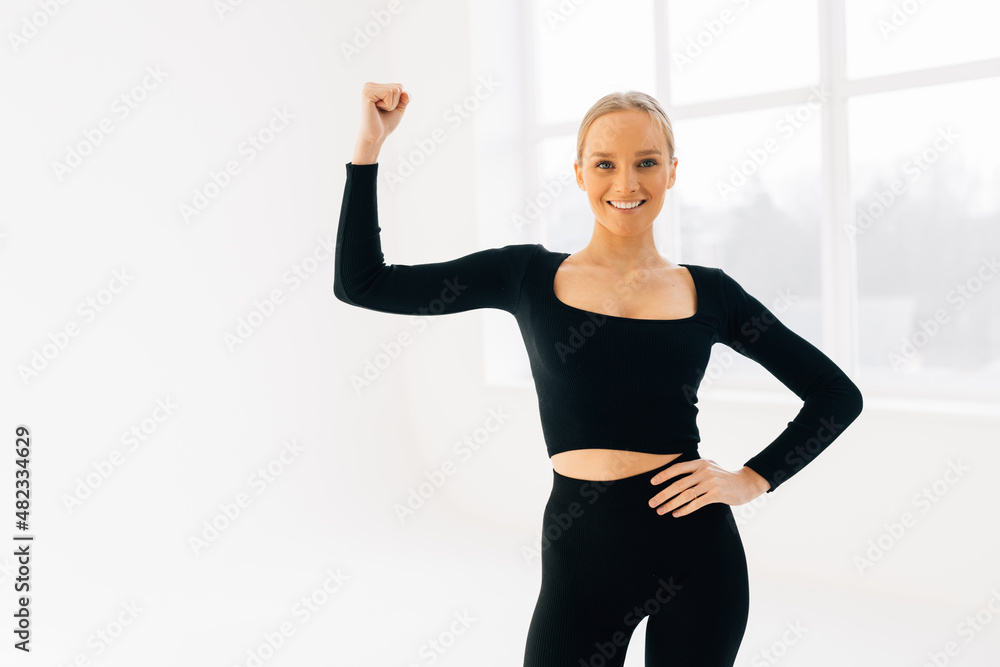 Cheerfully smiling sporty woman demonstrating biceps, isolated on white background Cheerfully smiling sporty woman demonstrating biceps, isolated on white background