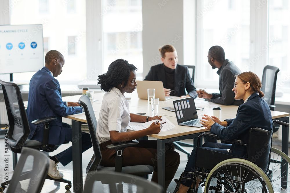 Portrait of successful businesswoman using wheelchair while speaking to employee in meeting, copy space Portrait of successful businesswoman using wheelchair while speaking to employee in meeting, copy space