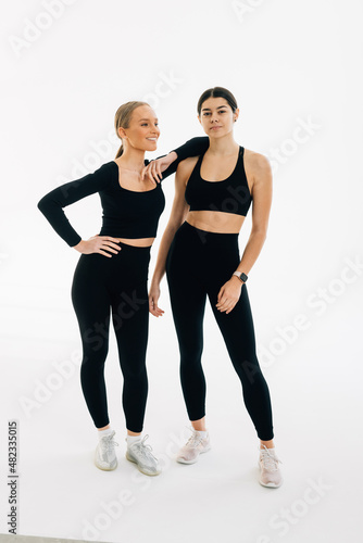 Portrait of two fit young women standing over white background