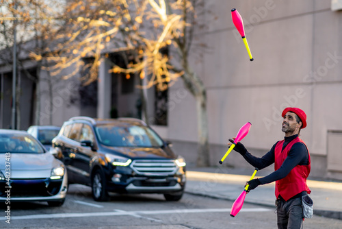 Street artist juggling pins in front of cars photo