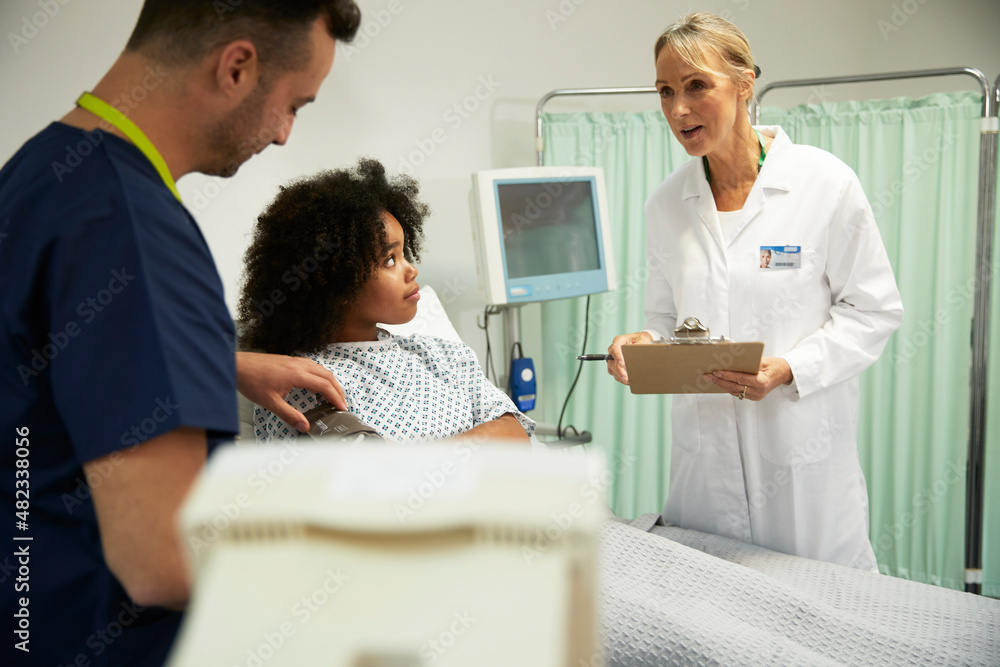 Female doctor talking to nurse examining blood pressure of patient at hospital Female doctor talking to nurse examining blood pressure of patient at hospital