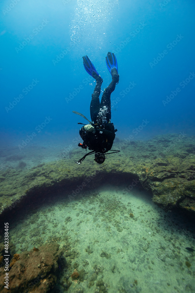 Young man diving upside down over ocean floor in sea