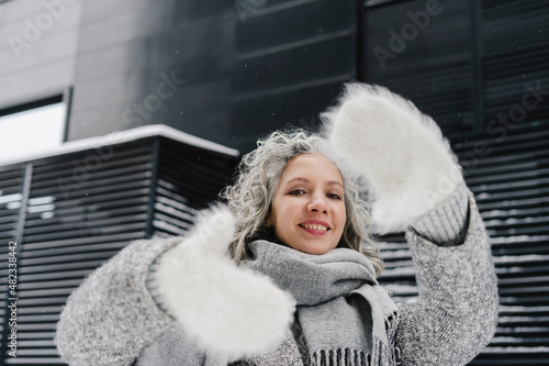 Smiling woman making wearing fur gloves making finger frame photo
