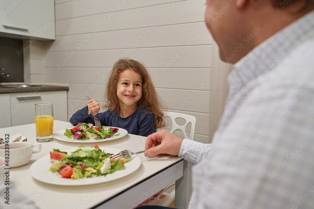Pleased girl enjoying her vegetable salad for breakfast Pleased girl enjoying her vegetable salad for breakfast