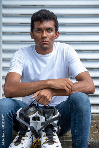 Portrait of confident young latino man wearing t-shirt and inline skates.