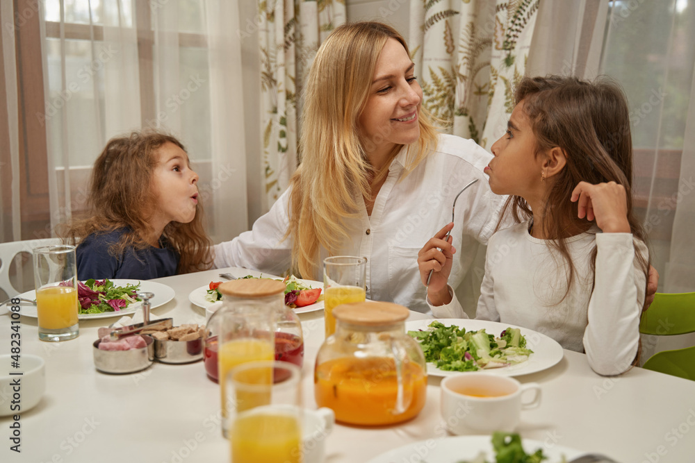 Charming young mother embracing her pretty daughters