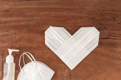 heart shape with white surgical masks for valentines day on a rustic and natural wooden background photo