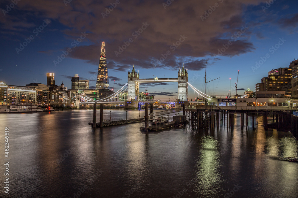 The iconic Tower Bridge in London, view to the illuminated Tower Bridge and skyline of London, UK, just after sunset.