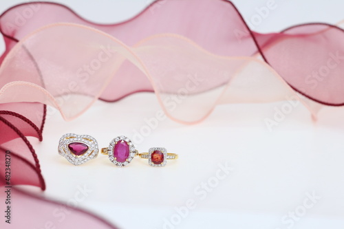 Red ruby rings with pink ribbon on white background. Jewelry set of gemstone for shop