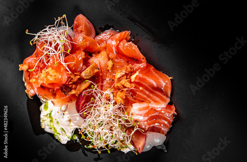Salty smoked slices gravlax salmon on plate on dark background photo