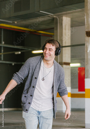 portrait of fashionable cool man on an industrial environment listening to music with earphones. vertical shot. High quality photo