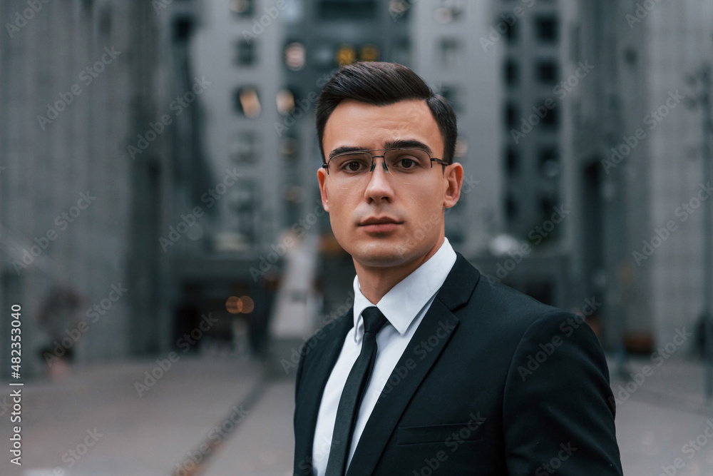 Portrait of businessman that is in black suit and tie is outdoors in the city Portrait of businessman that is in black suit and tie is outdoors in the city