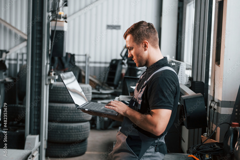 Man in uniform is working in the auto service Man in uniform is working in the auto service