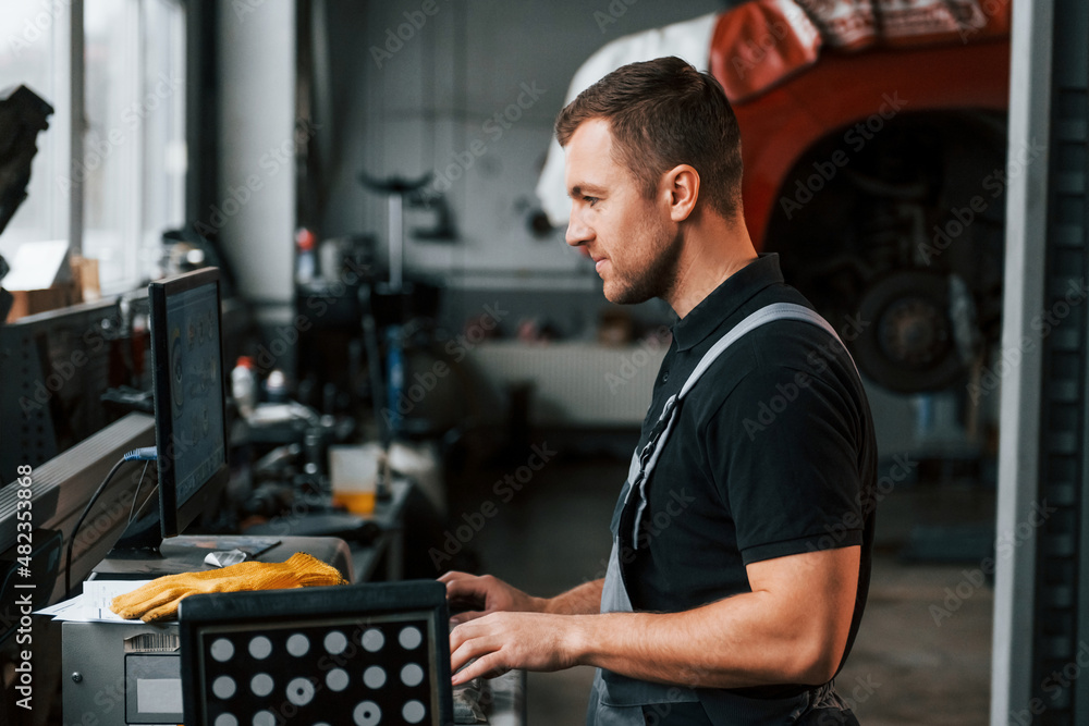 Work in progress. Man in uniform is in the auto service Work in progress. Man in uniform is in the auto service