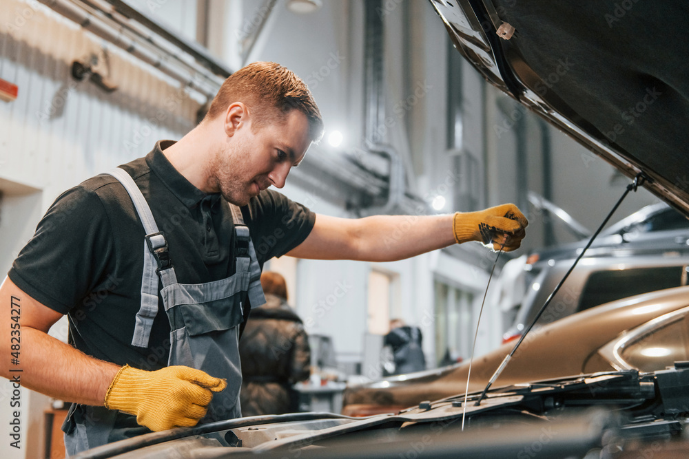 Ready to solve the problem. Man in uniform is working in the auto service Ready to solve the problem. Man in uniform is working in the auto service